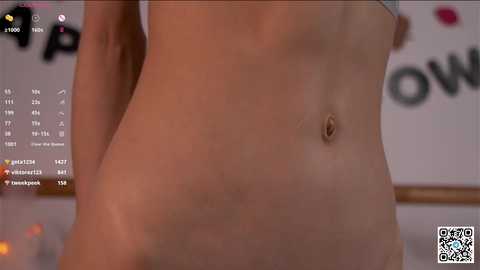 Media: A close-up video of a nude, light-skinned person's torso, showing a flat stomach and a small, light-colored navel, with a blurred background featuring a white wall and indistinct text.