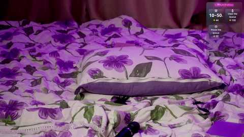 Media: A video shows a messy bed with purple and white floral bedding, a purple vibrator, and a black dildo on a pillow, set against purple curtains, with a digital clock showing 16:50.