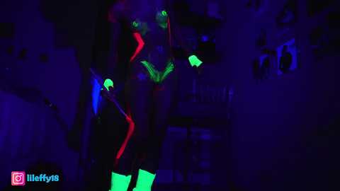 Media: Video of a person dressed in neon green and black bodysuit, glowing under UV light, surrounded by purple and blue hues, with a \"Lilify18\" watermark.