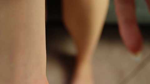 Media: A close-up, blurred video shows a pair of legs and feet, possibly female, with a focus on the thighs and calves. The background is out of focus, suggesting an indoor setting.