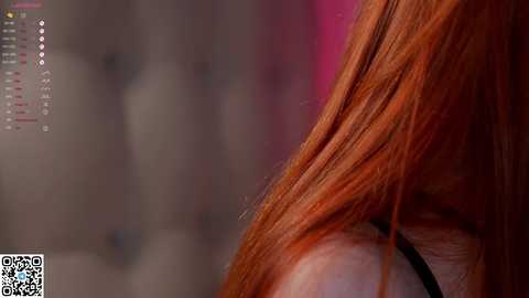 Media: A close-up video of a woman's long, fiery red hair cascading over her shoulder, with a blurred, pink and gray background.