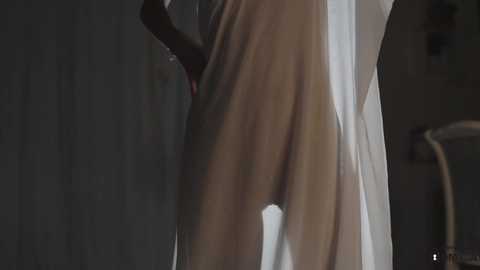 Media: A dimly lit video shows a close-up of a person's bare buttocks and thighs, partially covered by a white sheet, against a dark, blurred background.