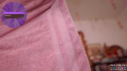 Media: Video of a person wrapped in a light pink towel, blurred background showing a child's bedroom with toys and a wooden bed.