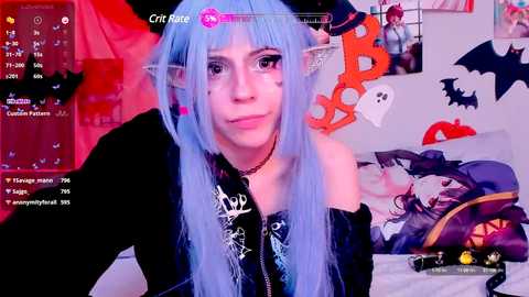 Media: Video of a pale-skinned woman with long, light blue hair, elf ears, and gothic makeup, wearing a black off-shoulder top. Background features a pink and black decor with bat and pumpkin decorations.