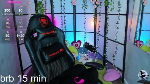 Media: Video of a gamer's setup with a black Razer chair, a pink headset, and a colorful gaming PC, surrounded by fairy lights and pink flowers in a cozy, pastel-themed room.