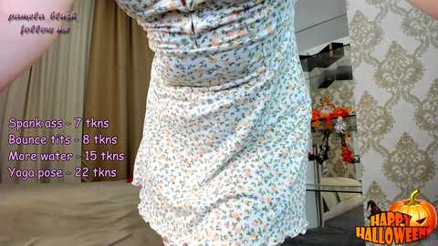 Media: A video featuring a woman in a white, floral dress, showcasing her hourglass figure. Text overlays provide fitness stats, and the background includes Halloween decor.