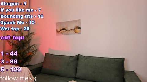 Media: A video of a beige sofa with cushions, a painting on the wall, and a fern plant. Text overlays show a kinky scenario with Ahengao, mentioning jumping, spanking, wet top, and cut top.