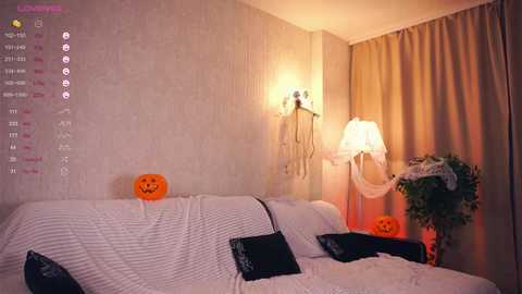 Media: A cozy, Halloween-themed bedroom with white bedding, orange pumpkins, a white lamp, and beige curtains.