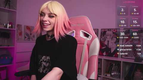 Media: Video of a young woman with pink and blonde hair, wearing a black graphic t-shirt and black choker, seated in a pink gaming chair. Background includes a pink-lit room with gaming posters, a white bookshelf, and digital overlays.