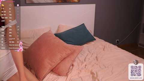 Media: Video of a cozy, minimalist bedroom with a beige bed, a teal pillow, and pink pillowcases. A QR code is visible in the bottom right corner.