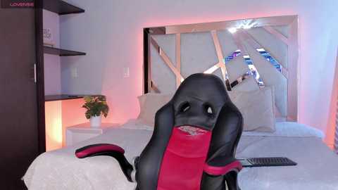 Media: Video of a black-and-red furry suit character sitting on a bed with white bedding, in a modern bedroom with a large mirrored wall and ambient lighting.