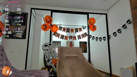 Media: A video of a Halloween-themed living room with a skeleton, orange pumpkins, black skull banners, and a beige inflatable slide.