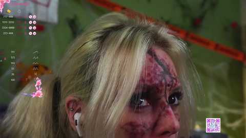 Media: Video of a blonde woman with a bloodied face, wearing white earphones, taken from a video game.