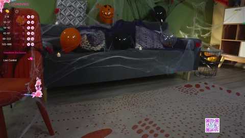 Media: Video of a Halloween-themed living room with a black couch adorned with orange and black cushions, spider webs, and pumpkins. The floor is decorated with red and white polka dots.