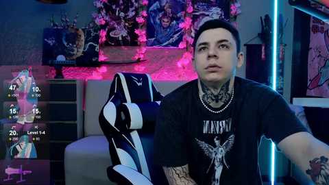 Media: Video of a tattooed man in a dark t-shirt with a gaming chair and colorful, neon-lit background.