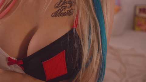 Media: Close-up video of a woman with long, straight, blonde hair wearing a black and red bra. A tattoo of \"Love is the answer\" is visible on her upper back.