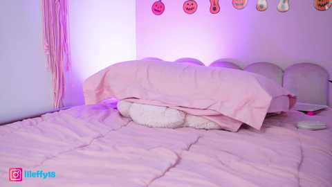 Media: A video of a soft pink bedroom with a plush bed, fluffy pillows, and a cozy, quilted blanket. Decorated with Halloween-themed decorations, including pumpkins and ghost cutouts, and a pink macrame wall hanging.