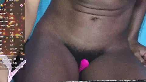 Media: A close-up video of a nude, dark-skinned person with a small, bright pink vibrator inserted into their pubic area. The background includes a live stream chat window with various messages.