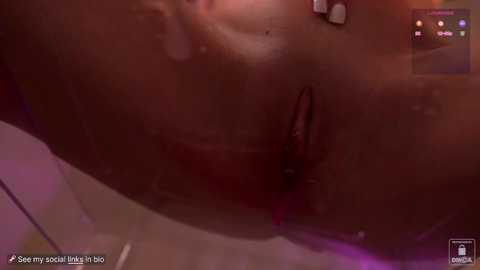 Media: Video of a close-up view of a human vulva, showing labia minora and clitoris, taken in a dimly lit room with soft pink hues.