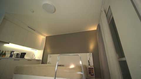 Media: Video of a minimalist, modern bathroom with beige walls, a white bathtub, stainless steel fixtures, and recessed lighting.