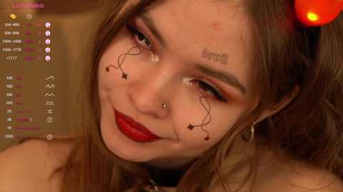 Media: Video of a young woman with fair skin, long brown hair, and a clown makeup mask featuring red lips and black lines. She wears a black choker. Background is blurred.