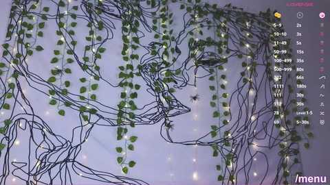 Media: Video of a dimly lit room with intricate black wire and green ivy vines hanging from the ceiling, creating a whimsical, bohemian atmosphere. A digital menu interface is visible in the top right corner.