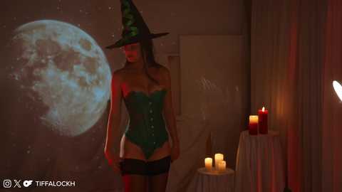 Media: Video of a woman in a green witch costume, wearing a pointy hat, corset, and short skirt, standing in a dimly-lit room with a full moon projection on a wall, candles on a table, and a shadowy figure.