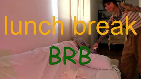 Media: Video of a woman in striped shirt and jeans fixing a white bed in a dimly lit room with text overlay: \"Lunch break BRRB.\