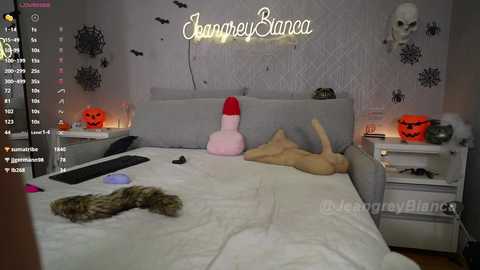 Media: Video of a Halloween-themed bedroom with a gray bed, plush toys, and a \"Johnnycake\" neon sign.