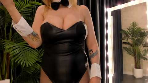 Media: Video of a curvy, fair-skinned woman with blonde hair in a black bunny costume, featuring a tight, strapless bodysuit, white cuffs, and a black bow tie. She stands in front of a mirror with a lit vanity light.