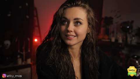 Media: Video of a wet-haired, fair-skinned woman with a radiant smile, wearing a black jacket, in a dimly lit room with red lighting, blurred background, and \"I love you\" watermark.