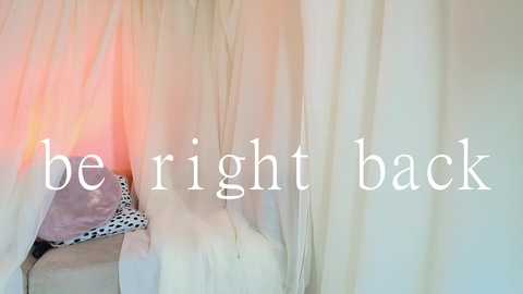 Media: Video of a white, sheer curtain with a subtle pink hue, featuring a leopard-print bikini bottom peeking through. Text overlay reads \"be right back\" in a clean, sans-serif font.