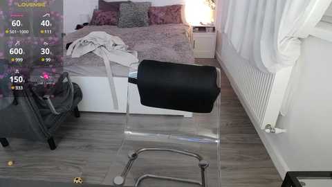 Media: A video of a messy bedroom with a clear chair, a bed, and a radiator. The room has light-colored walls, a gray rug, and a white radiator.