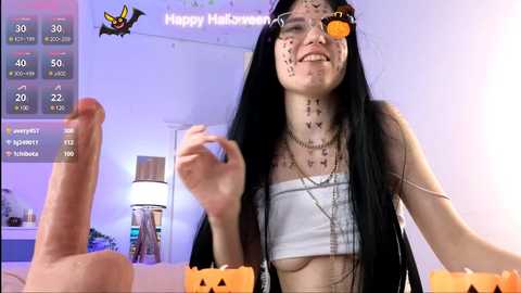 Media: Video of an Asian woman with long black hair and a white crop top, wearing a Halloween-themed face mask and a cat ear headband, holding a carved pumpkin in a room with a Happy Halloween sign.