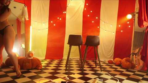 Media: A video of a vibrant, circus-themed room with red and white striped curtains, checkered floor, three black barstools, teddy bears, and hanging string lights.