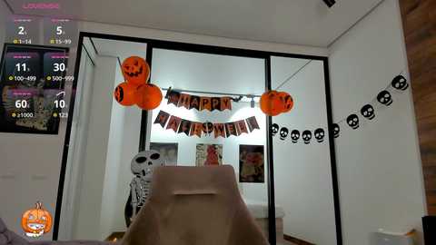 Media: A video of a living room decorated for Halloween. The room features a large TV, a skeleton, and a \"Trick or Treat\" banner with jack-o'-lanterns.