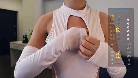 Media: A video of a person wearing a white, sleeveless bodysuit with a keyhole neckline, revealing a hint of cleavage, in a modern, minimalist kitchen.