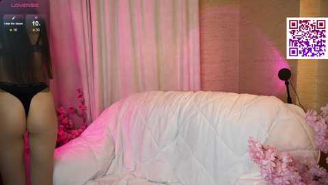 Media: A video of a woman in black lingerie standing beside a bed with pink sheets, surrounded by pink flowers and a QR code in the top right corner.