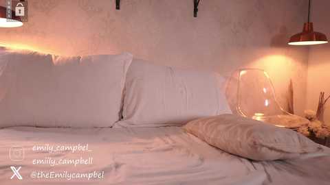 Media: A video of a cozy bedroom with a white bed, two glass lamps, and a beige pillow. The walls are textured and the lighting is warm.