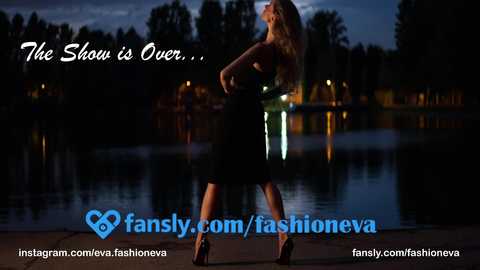 Media: Video of a blonde woman in a black dress, standing confidently with a lit-up cityscape in the background. Text reads, \"The Show is Over...\" and \"fansly.com/fashioneva.\