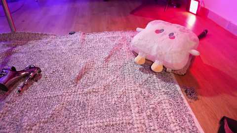 Media: Video of a plush SpongeBob SquarePants toy lying on a gray carpet, surrounded by a hammer and bloodstains, with red lighting and a wooden floor in the background.