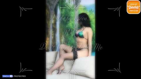 Media: Video of a curvaceous woman with long black hair, wearing a teal bra, black lace garter belt, and stockings, sitting on a beige couch, with a blurred outdoor forest background. Text overlay reads, \"Don't Forget to Kiss Me.\