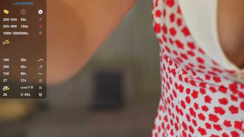 Media: Video of a woman in a red and white polka-dot dress, blurred background, focus on her torso and arm.