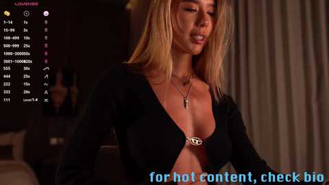 Media: Video of a blonde woman in a low-cut black top, indoors, with a \"hot\" content warning overlay.