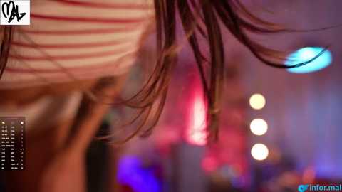 Media: A blurred video shows a young woman with shoulder-length brown hair, wearing a striped top, dancing in a dimly lit, vibrant nightclub with purple and pink lights.