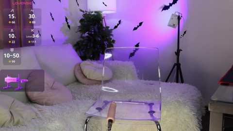 Media: Video of a minimalist, white-themed bedroom with a clear chair, plush pillows, and a large plant, bathed in purple and blue lighting.