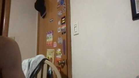 Media: Video of a child's bedroom with a wooden door adorned with colorful stickers, a white wall, and a beige chair.