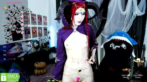 Media: Video of a pale-skinned, red-haired woman in a revealing purple and white costume with horns, standing in a Halloween-themed room with decorations and a plush shark toy.