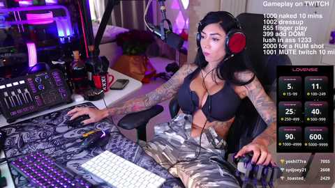 Media: Video of a tattooed, dark-haired woman in black lingerie, seated at a gaming desk, with Twitch stream stats overlay.