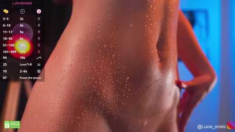 Media: Video of a nude woman's back and side, with water droplets glistening under blue light. She has a slim physique and is viewed from behind.